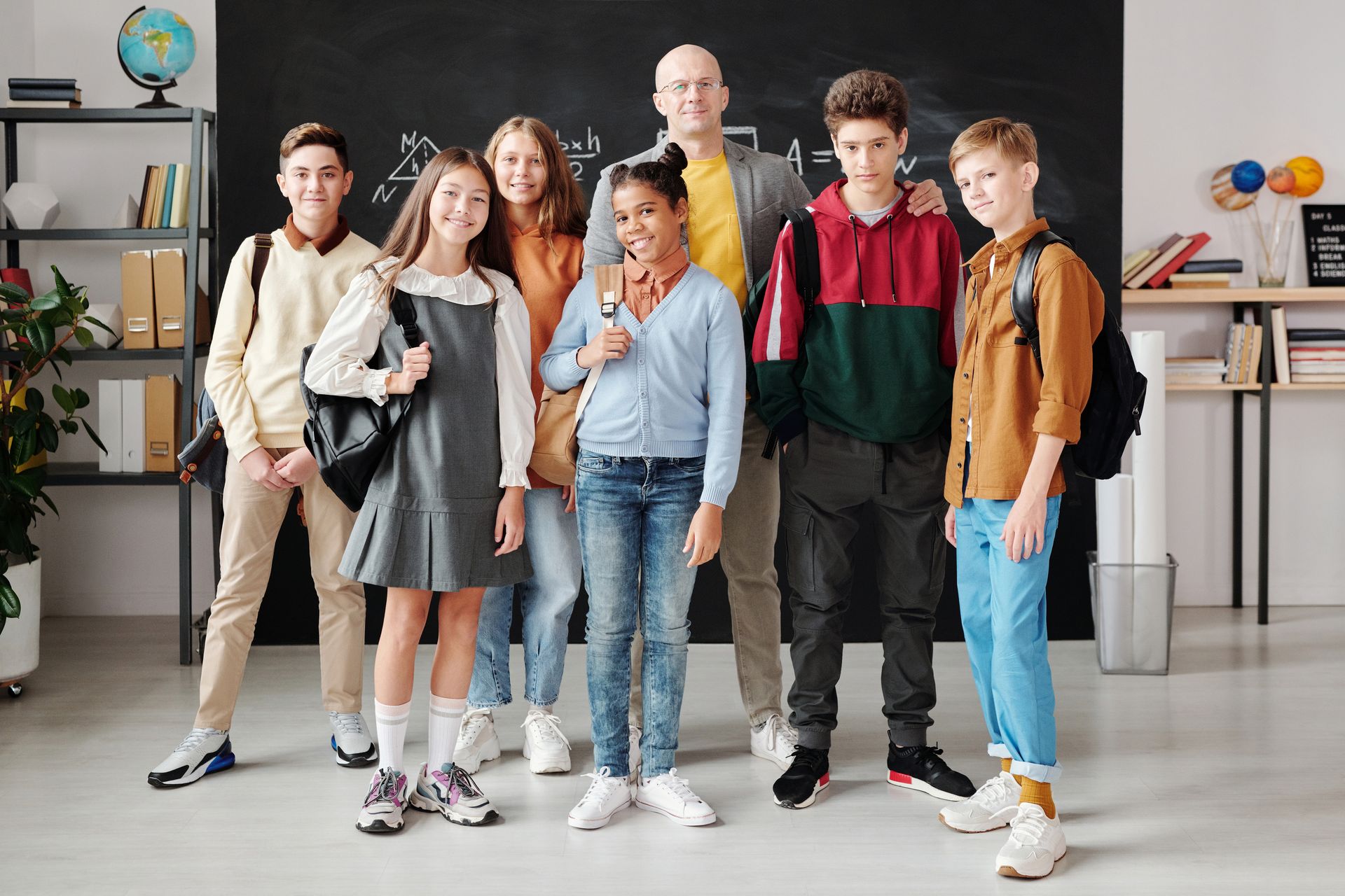 A teacher standing with a diverse group of smiling students in a classroom.